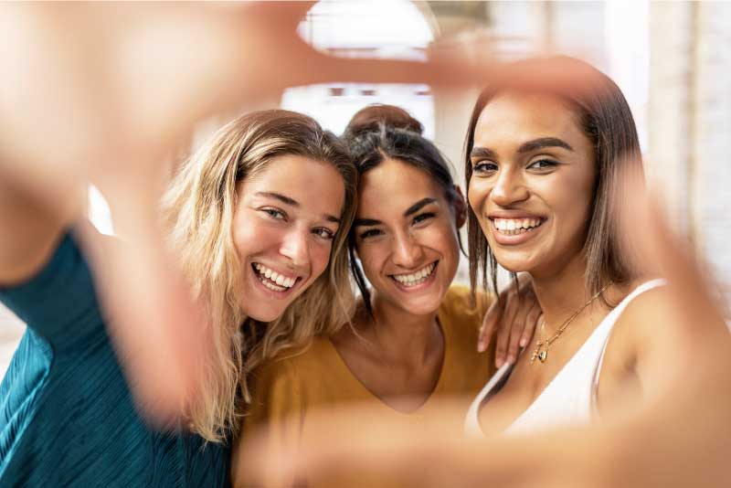 three multiracial female friends taking selfie